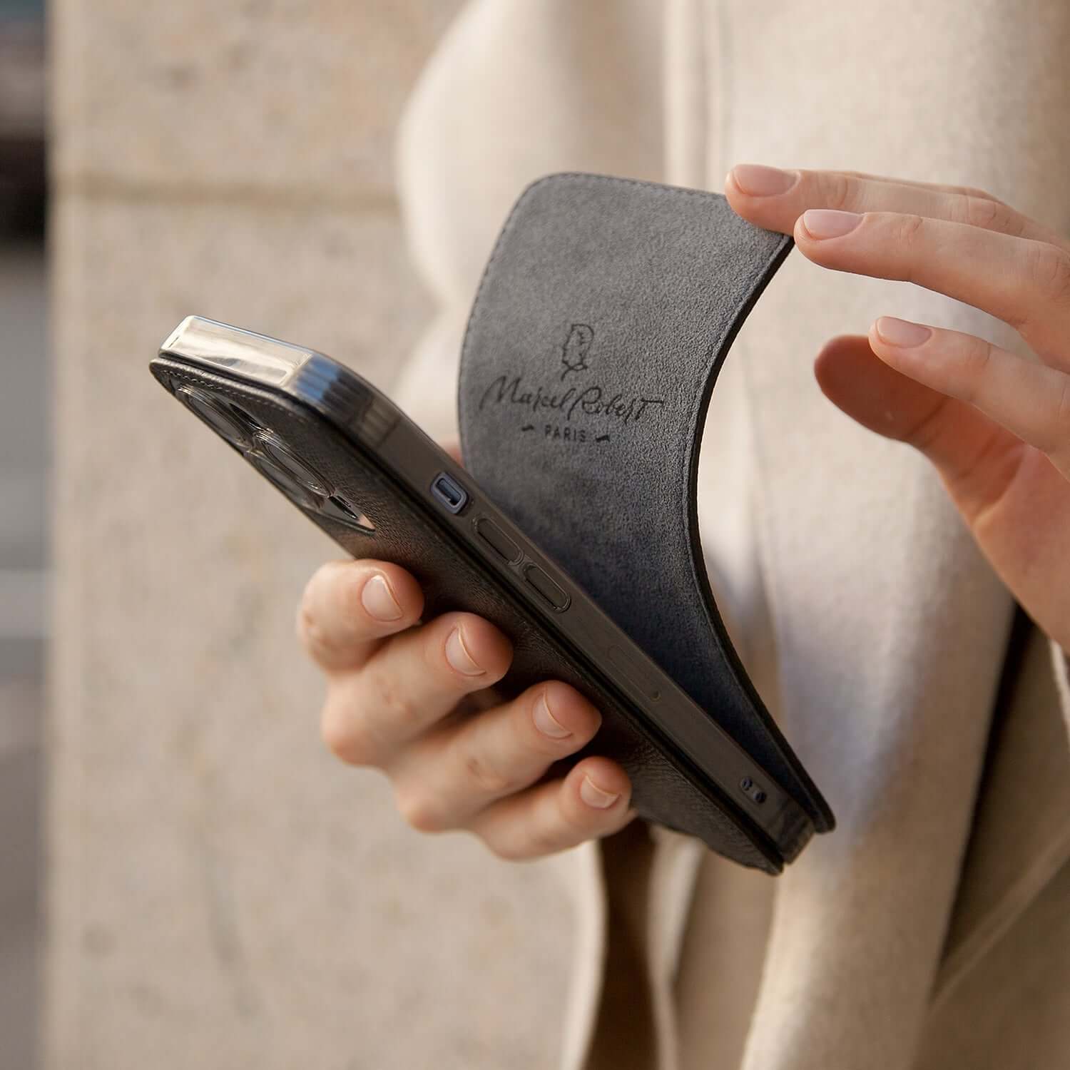 case iPhone 15 Pro Max black Safiano held in hand with stylish design and logo visible.