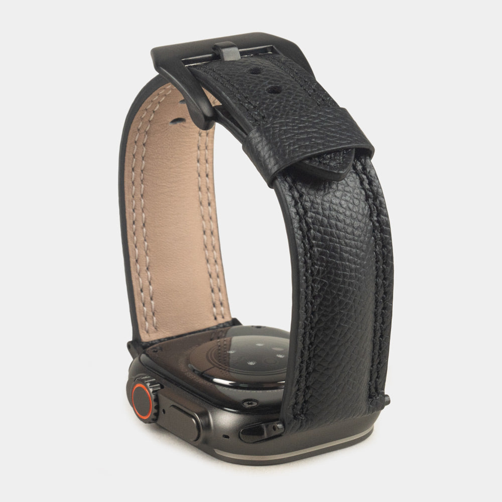 Apple Watch Ultra bandje heren 49 mm zwart Epsom leer met zwarte gespen — verhoogd driekwart achteraanzicht op de zwarte kast, crèmekleurige Alsavel voering en geverfde rand