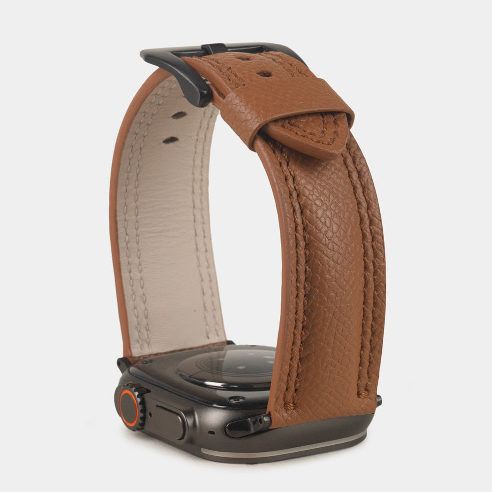 Apple Watch Ultra bandje heren 49 mm goud Epsom leer met zwarte gespen — verhoogd driekwart achteraanzicht op de zwarte kast, crèmekleurige Alsavel voering en geverfde rand