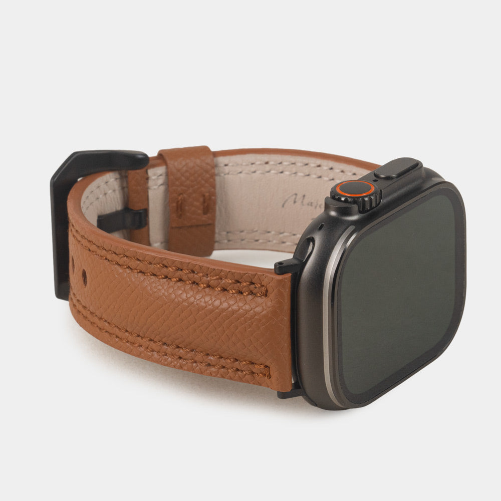Apple Watch Ultra bandje heren 49 mm goud Epsom leer met zwarte gespen — driekwart vooraanzicht met de wijzerplaat van de Ultra, de gesp en de leren lus