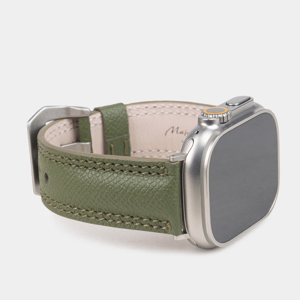 Apple Watch Ultra bandje heren 49 mm kakigroen Epsom leer met titanium gespen — driekwart profiel op de titanium Ultra-kast, crèmekleurige Alsavel voering met stempel Marcel Robert Paris