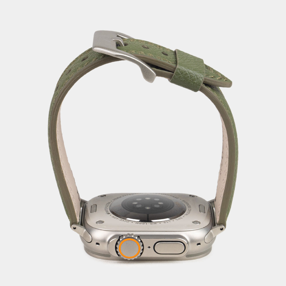 Apple Watch Ultra bandje heren 49 mm kakigroen Epsom leer met titanium gespen — zijaanzicht, bandje open boven de kastbodem, welving en geverfde rand