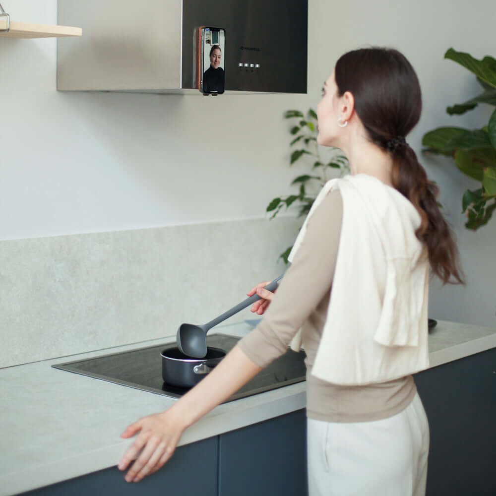 Person using a smartphone in leather made case with magnets on a kitchen appliance, likely a microwave and cooking dinner