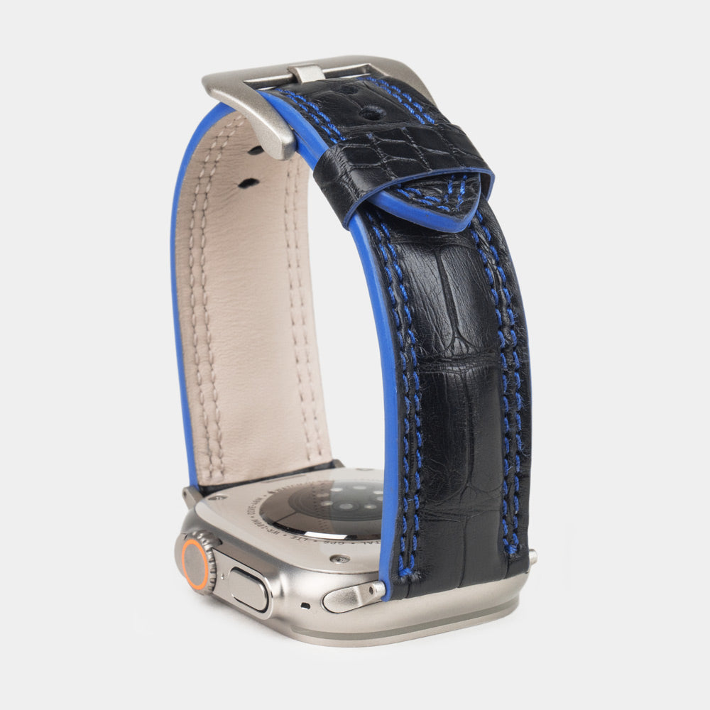 Apple Watch Ultra 49 mm aus schwarzem Alligatorleder, Naht und Kante in Blau, mit Adaptern und Schnalle aus Titan | Nahaufnahme der quadratischen Schuppen und der Doppelnaht in Blau