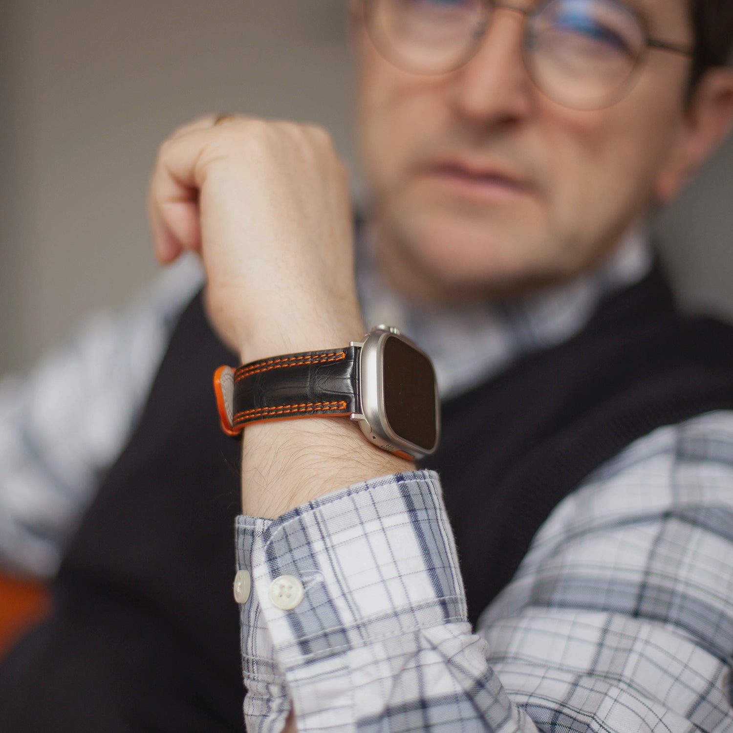 Apple Watch Ultra 49 mm aus schwarzem Alligatorleder, Naht und Kante in Orange, mit Adaptern und Schnalle aus Titan | Lifestyle-Foto, das Armband am Handgelenk eines Mannes