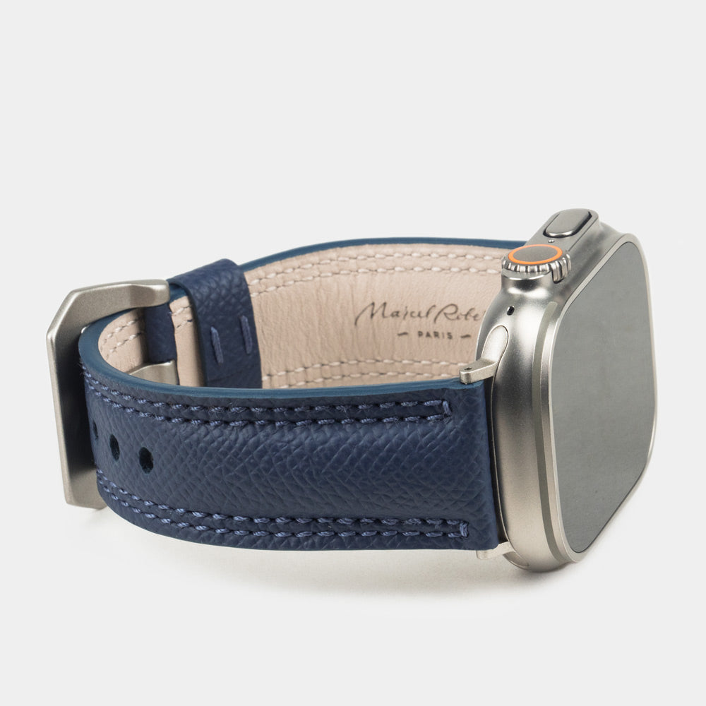 Apple Watch Ultra bandje heren 49 mm blauw Epsom leer op de titanium kast van de Ultra — driekwart profiel met de crèmekleurige leren voering met stempel Marcel Robert Paris