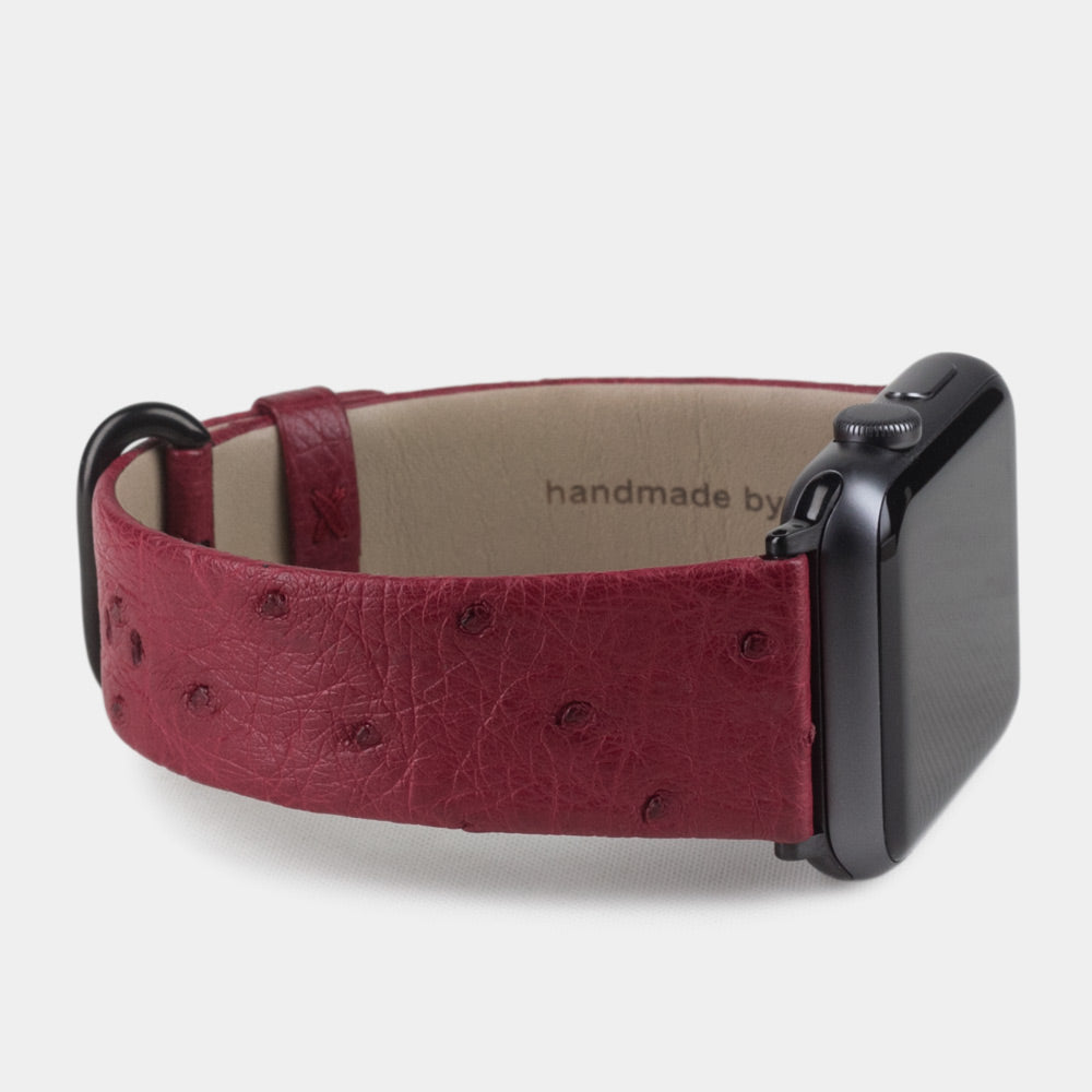 Strap for the Apple Watch 41/42 mm in fuchsia ostrich leather, with black adapters and buckle | watch case on bottom to see leather texture, inner lining and the buckle