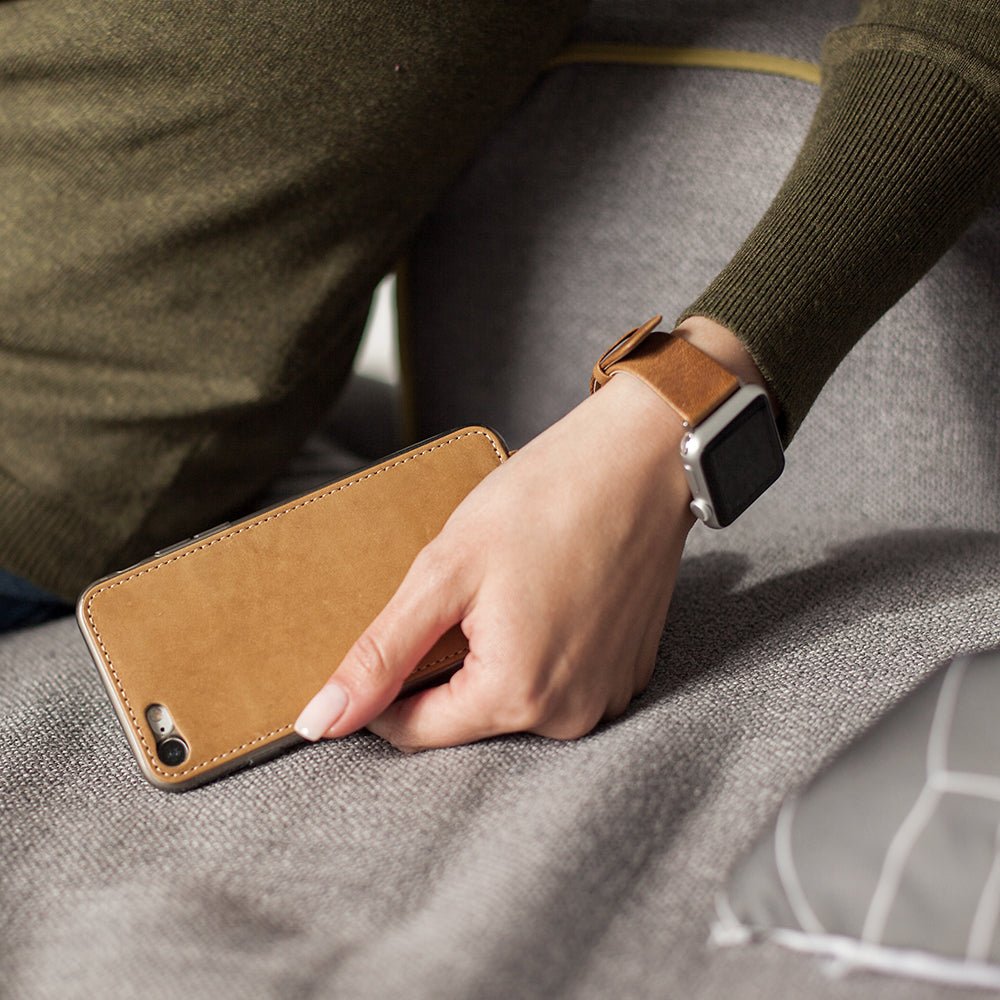 Lederen hoesje Vintage voor iPhone SE in de hand van een vrouw, rustend op een bank