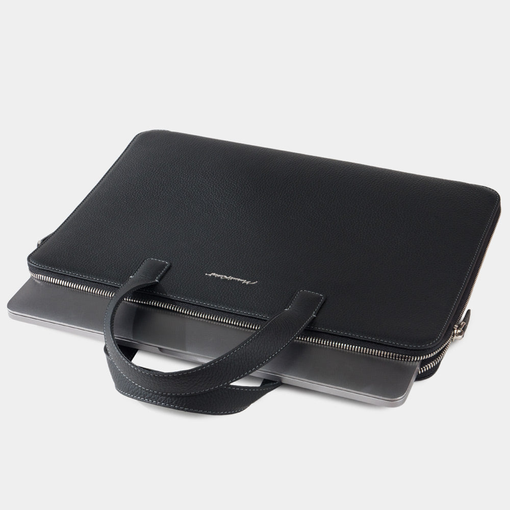 Slim 17 inch black leather laptop bag holding laptop, structured minimalist design