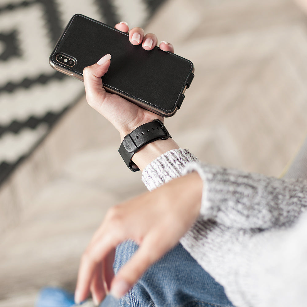 Leren flip-hoesje zwart voor iPhone XS Max - in de hand van een vrouw, achteraanzicht met de gladde leerafwerking