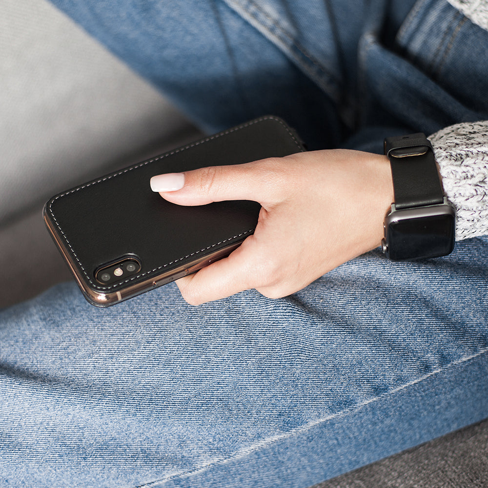 Black leather case for iPhone X in woman's hand, resting on her lap