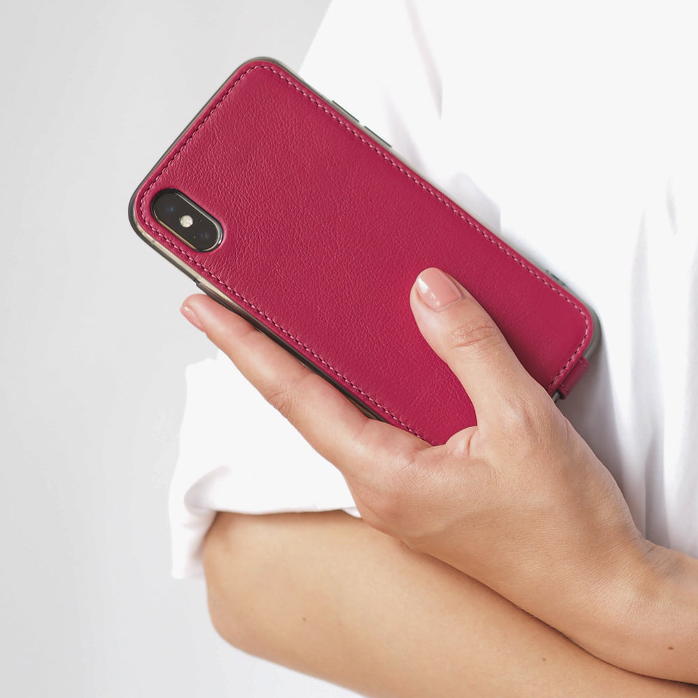 Fuchsia leather flip case for iPhone X in woman's hand, held against her side