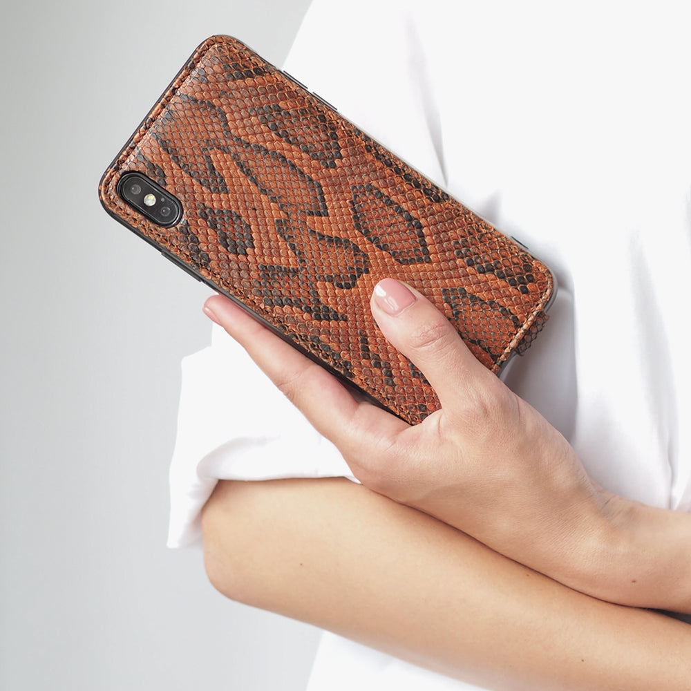 Python leren flip-hoesje goud voor iPhone X - in de hand van een vrouw, close-up tegen een wit shirt