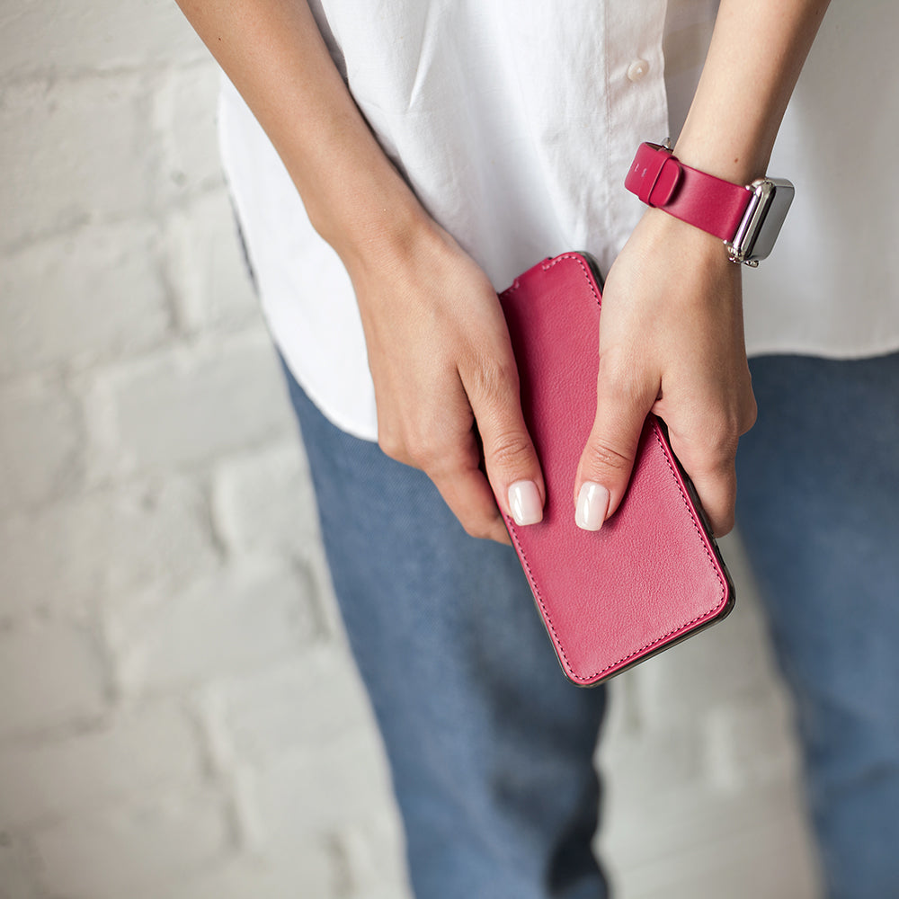Leren flip-hoesje fuchsia voor iPhone XS Max - in de handen van een vrouw, gesloten klep vastgehouden ter hoogte van de taille