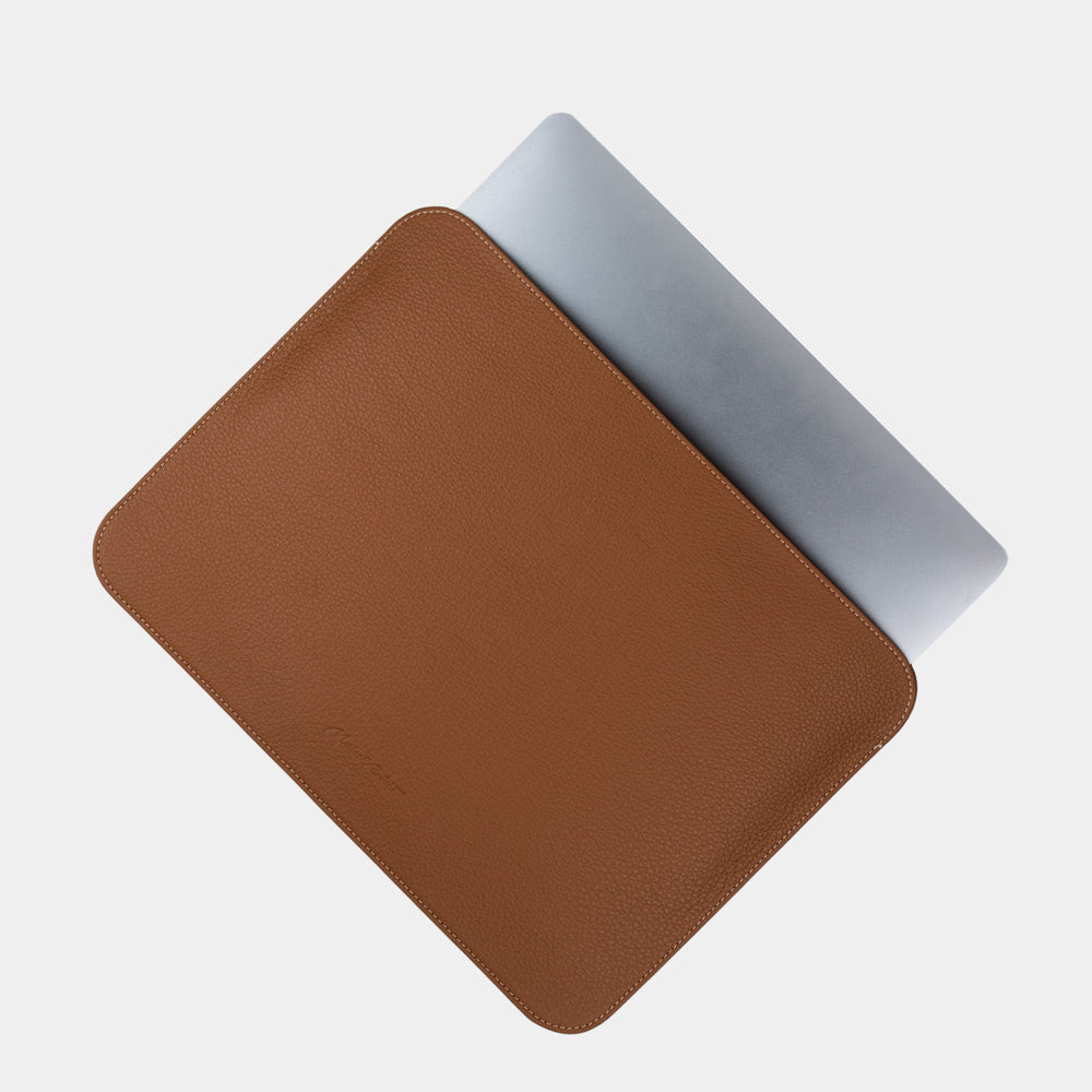 Leren laptophoes 14 inch in goud, met MacBook deels erin geschoven — slanke minimalistische MacBook hoes