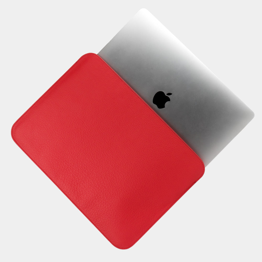 Leren laptophoes 14 inch in rood, met MacBook deels erin geschoven — slanke minimalistische MacBook hoes