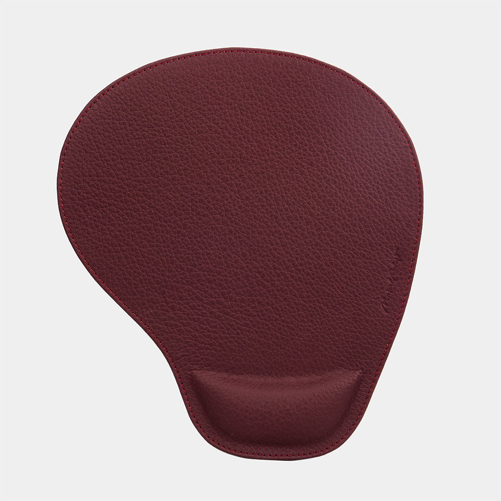 Tappetino mouse in pelle bordeaux visto dall'alto, forma a goccia e firma impressa