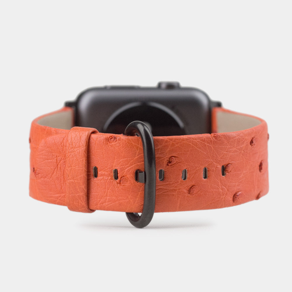 Strap for the Apple Watch 41/42 mm in orange ostrich leather, with black adapters and buckle | watch case on bottom to see leather texture, inner lining and the buckle