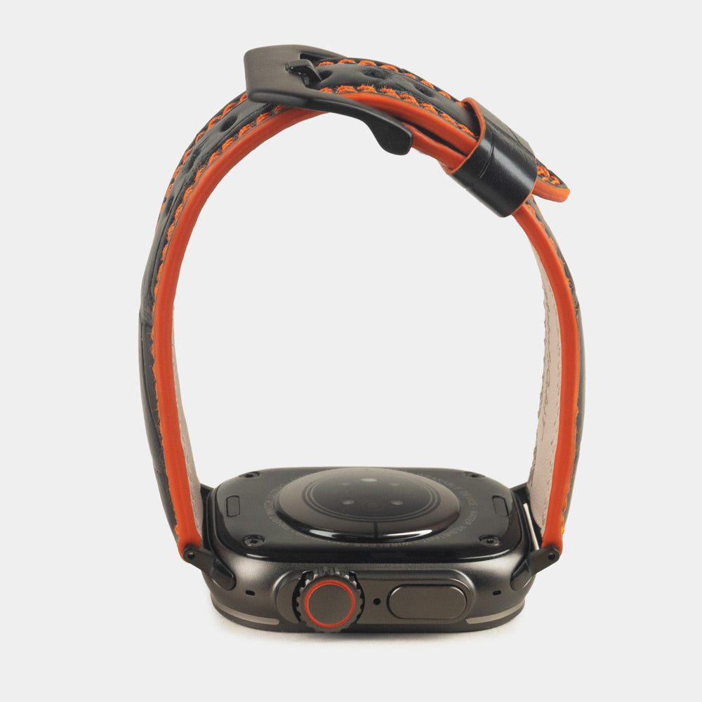 Apple Watch Ultra 49 mm aus schwarzem Alligatorleder, Naht und Kante in Orange, mit schwarzen Adaptern und Schnalle | Gehäuse unten, um das Armbandprofil und die orange gefärbte Kante zu sehen