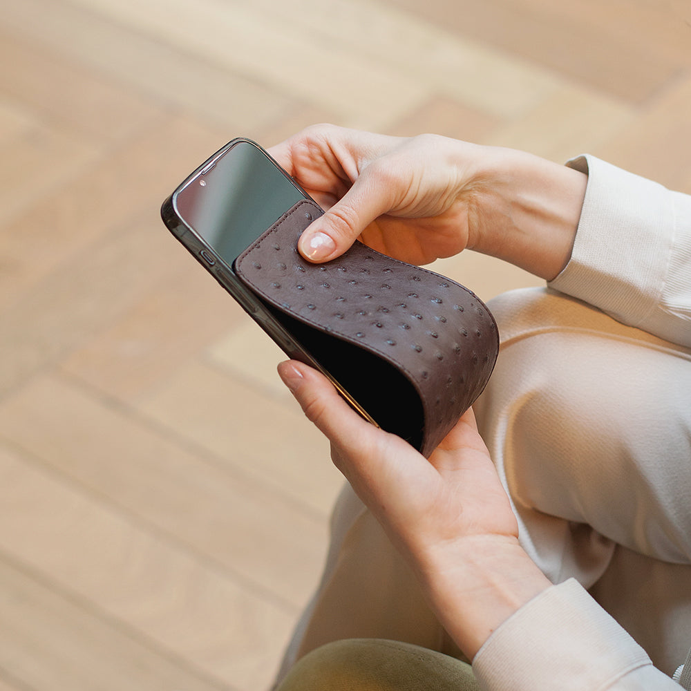 Opening Marcel Robert brown ostrich leather iPhone 13 Pro case revealing the screen with one hand