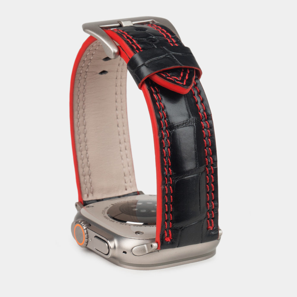 Apple Watch Ultra 49 mm aus schwarzem Alligatorleder, Naht und Kante in Rot, mit Adaptern und Schnalle aus Titan | Nahaufnahme der quadratischen Schuppen und der Doppelnaht in Rot