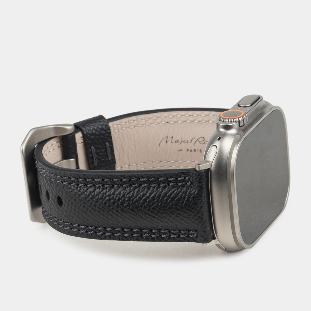Apple Watch Ultra bandje heren 49 mm zwart Epsom leer op de titanium kast van de Ultra — driekwart profiel met de crèmekleurige leren voering met stempel Marcel Robert Paris