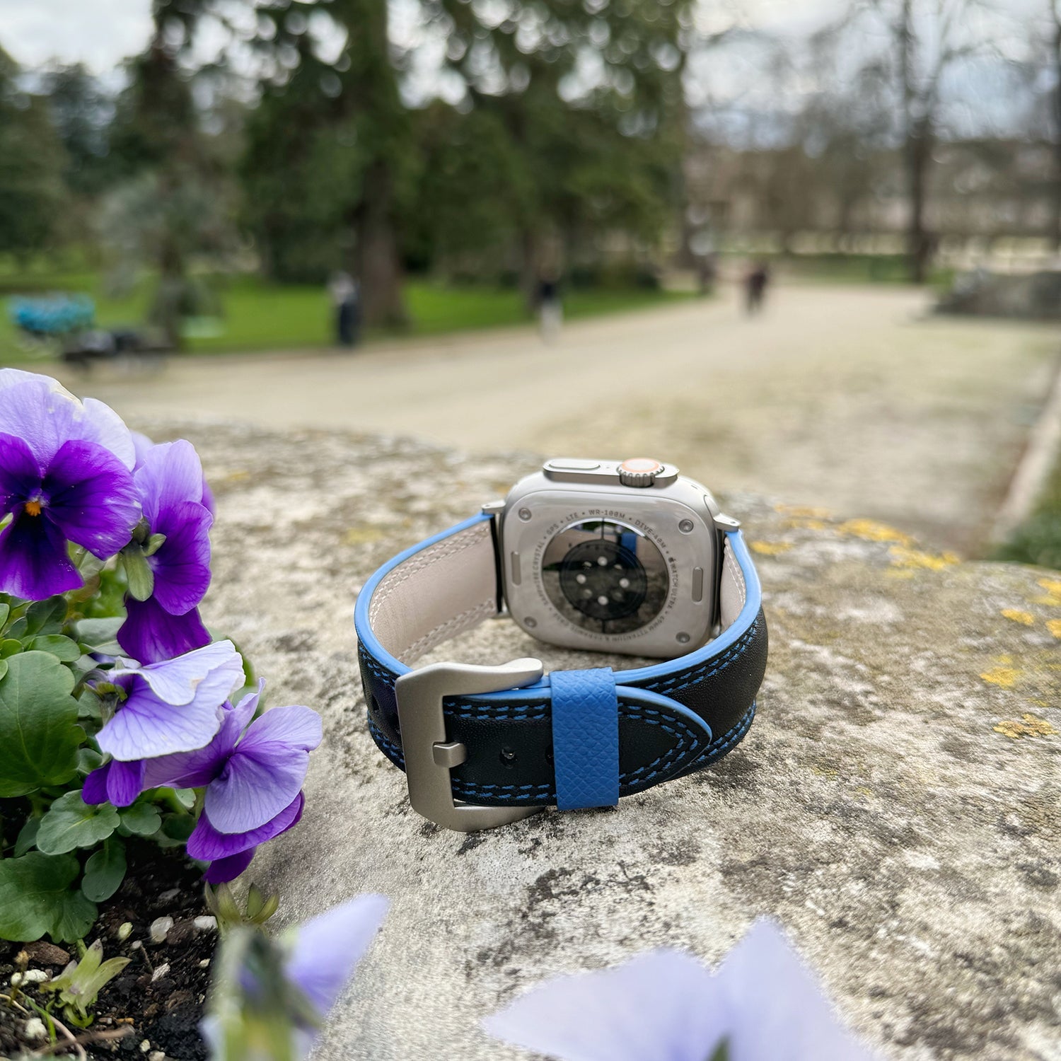 Bracelet homme Apple Watch Ultra 49 mm en cuir de veau lisse noir à tranche bleue et ses adaptateurs couleur titane - vue en situation