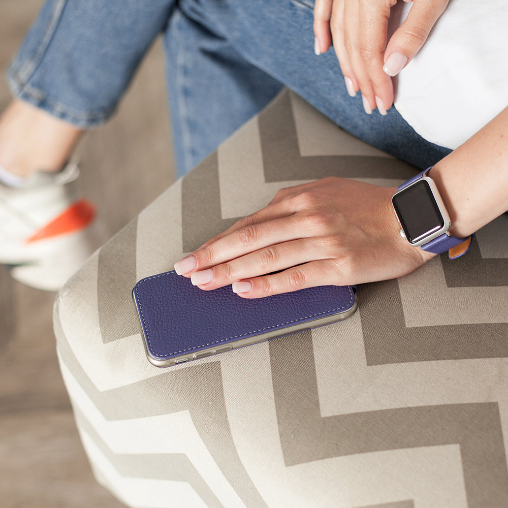 Funda de piel Morado para iPhone SE en la mano de una mujer, apoyada en una silla