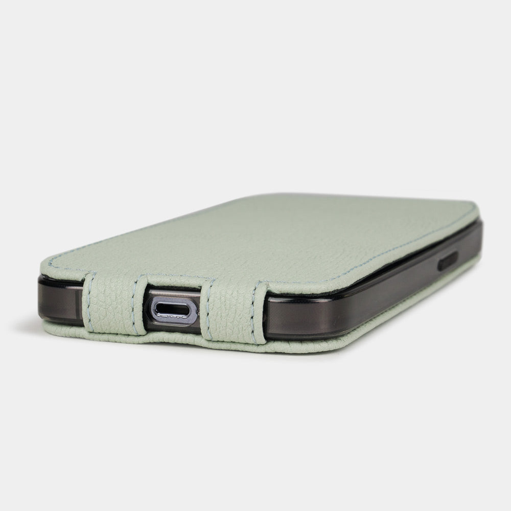 Cover in pelle di vitello verde pastello per iPhone 15 Plus – vista dal basso con l’apertura della porta USB-C e i bordi cuciti a mano