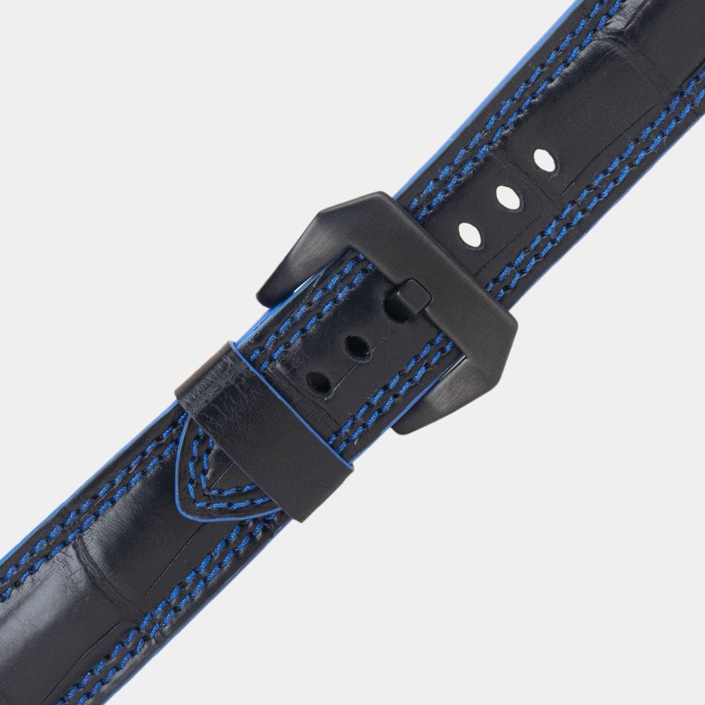 Apple Watch Ultra 49 mm aus schwarzem Alligatorleder, Naht und Kante in Blau, mit schwarzen Adaptern und Schnalle | Nahaufnahme der quadratischen Schuppen und der Doppelnaht in Blau